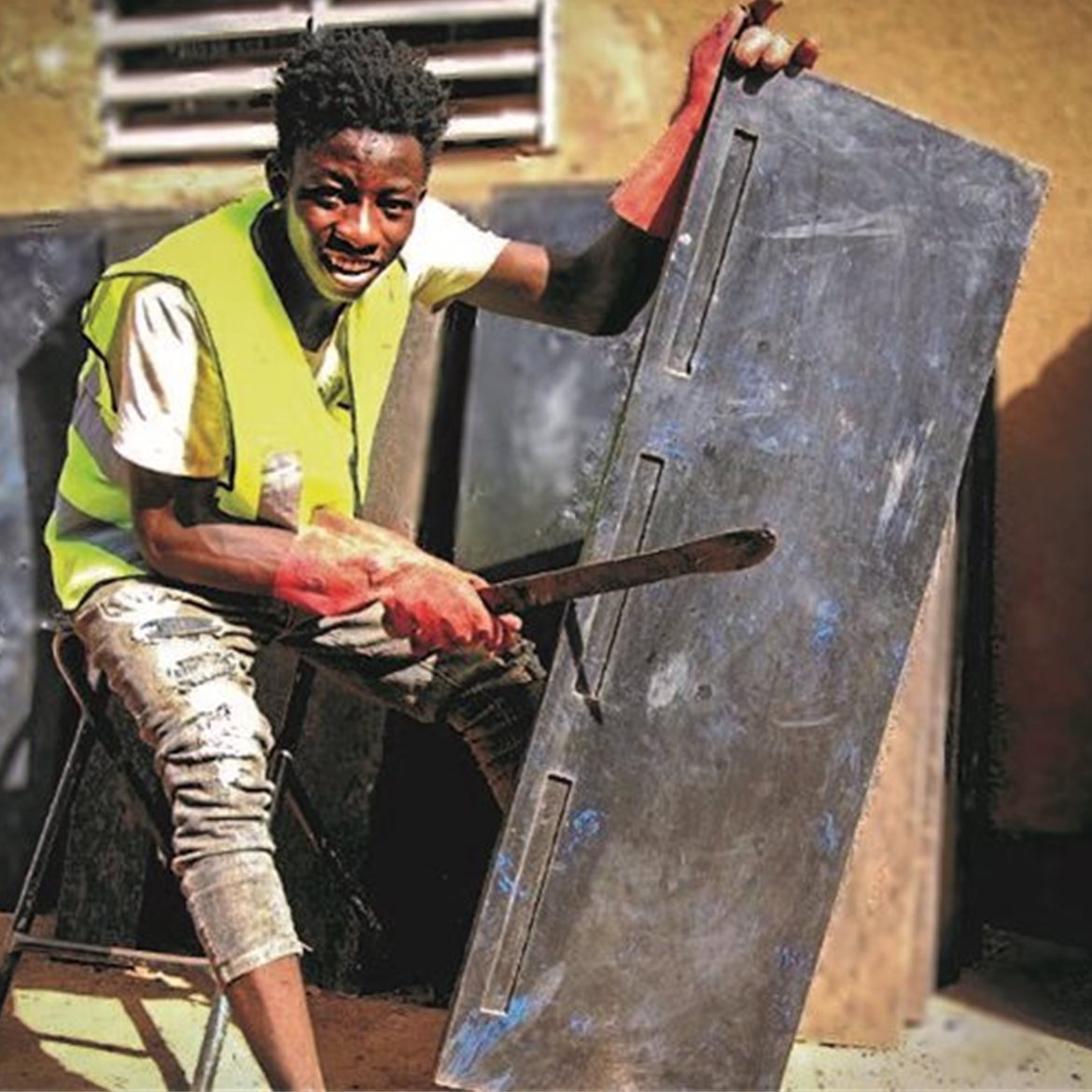Ung gutt fra Burkina Faso som jobber med resirkulerte skolepulter. 